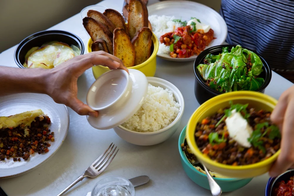 Hokanbowls-hands-at-table-with-food